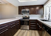 Thumbnail 27 of 57 - Apartments for Rent Laguna Niguel CA - Pointe Niguel - Kitchen with Wood-Style Floor, Brown Cabinets, White Quartz Countertops, and Stainless Steel Appliances at Pointe Niguel, Laguna Niguel, CA