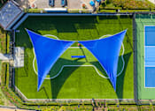 Thumbnail 35 of 57 - A tennis court with a blue shade structure.