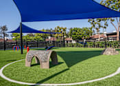 Thumbnail 37 of 57 - A playground with a blue canopy and a white pathway.