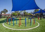Thumbnail 39 of 57 - A playground with a blue shade structure and red and blue swings.