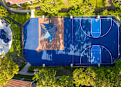 Thumbnail 56 of 57 - An aerial view of a basketball court surrounded by trees.