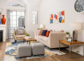 Thumbnail 16 of 59 - Apartments for Rent in Miracle Mile Los Angeles, CA - The Preston - Living Room with Plank Wood Style Flooring, Area Rug, Sofa, Ottoman Stools, Armchair, Side Table with Lamps, Coffee Table, High Ceiling, and Glass Door with Access to Balcony.