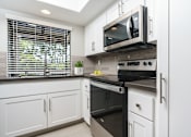Thumbnail 29 of 39 - Kitchen with bay window, stove and microwave at Ridgecrest, Lake Forest, CA, 92630