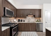 Thumbnail 3 of 39 - A kitchen with a black stove top oven and a black and white tiled backsplash.