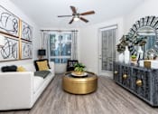 Thumbnail 5 of 39 - A living room with a white couch, a gold coffee table, and a mirror on the wall.