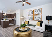 Thumbnail 4 of 39 - A modern living room with a white couch, a coffee table, and a painting on the wall.