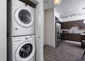 Thumbnail 10 of 39 - A white front loading washing machine is in a laundry room.