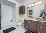 Thumbnail 9 of 39 - A bathroom with a white toilet, a white bathtub, a sink, and a mirror.