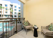 Thumbnail 12 of 39 - A balcony with two chairs and a table with a plant on it.