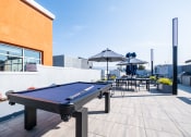 Thumbnail 16 of 18 - a pool table on a rooftop terrace with umbrellas and tables