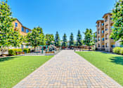 Thumbnail 12 of 40 - an empty park with trees and a playground in front of an apartment building