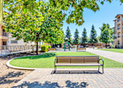 Thumbnail 5 of 40 - a park bench in front of a grassy area with trees and a playground