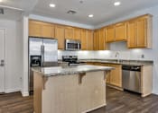 Thumbnail 38 of 40 - San Jose, CA Apartments for Rent - Aviara - Gourmet Kitchen with Wood-Style Flooring, Kitchen Island, Granite Countertops, Natural Cabinetry, and Stainless Steel Whirlpool Appliances.