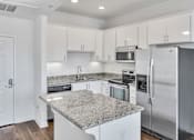 Thumbnail 26 of 40 - a kitchen with white cabinets and stainless steel appliances and granite counter tops