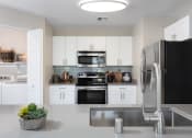Thumbnail 5 of 36 - Kitchen with Stainless Steel Appliances & Washer & Dryer Room at Montrachet Apartments, California