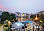 Thumbnail 13 of 19 - Pet-Friendly Apartments in Upland, CA - Park Central Apartments - Swimming Pool with a Spa, Sun Loungers, Lounge Seats, Pergola, and Umbrellas, Surrounded by a Metal Fence, Trees, and Landscaping.