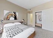 Thumbnail 5 of 19 - Dog-Friendly Apartments in Upland, CA - Park Central Apartments - Bedroom with Carpet Flooring, Large Bed, Nightstands, Lamps, Abstract Wall Art, and Oversized Closets with a Sliding Door.