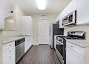 Thumbnail 7 of 19 - A kitchen with white cabinets and stainless steel appliances.