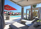Thumbnail 14 of 87 - A patio with a red umbrella and a pool in the background.