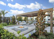 Thumbnail 32 of 87 - A patio with a fire pit surrounded by plants.