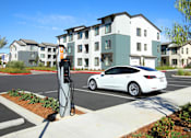 Thumbnail 37 of 87 - A white car is charging at an electric vehicle charging station.