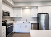 Thumbnail 54 of 87 - A modern kitchen with white cabinets and stainless steel appliances.