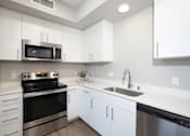 Thumbnail 59 of 87 - A modern kitchen with white cabinets and stainless steel appliances.