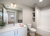 Thumbnail 60 of 87 - A white bathroom with a toilet, sink, and mirror.