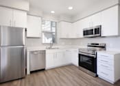 Thumbnail 64 of 87 - West Sacramento, CA Apartments with In-Unit Washer and Dryer - The Strand - Gourmet Kitchen with Prep Island, Quartz Countertops, Stainless Steel Appliances, White Modern Custom-Wood Cabinetry, and Wood-Style Flooring.