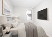 Thumbnail 71 of 87 - A bedroom with a bed, nightstand, lamp, and a painting on the wall.