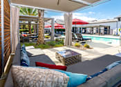 Thumbnail 16 of 85 - A patio with a couch, pillows, and a pool in the background.