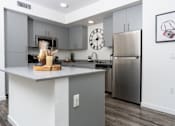 Thumbnail 51 of 85 - A modern kitchen with a stainless steel refrigerator and a wooden cutting board on the island.