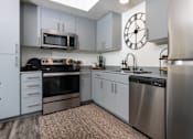 Thumbnail 49 of 85 - A modern kitchen with stainless steel appliances and a clock on the wall.