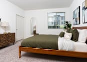 Thumbnail 60 of 85 - A bedroom with a bed, nightstand, and a plant.