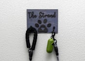 Thumbnail 71 of 85 - A green pendant hangs from a black cord on a wall.