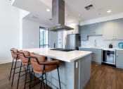Thumbnail 22 of 50 - a kitchen with a large island with four stools in front of it at Strata at Mission Bay, San Francisco, California