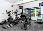 Thumbnail 27 of 39 - a gym with various cardio equipment in a room with windows at Sunstone Place, Riverside, CA, 92505