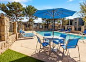 Thumbnail 3 of 142 - A pool area with blue chairs and an umbrella.
