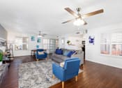 Thumbnail 5 of 142 - A living room with a blue sofa and a ceiling fan.