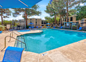 Thumbnail 1 of 142 - A swimming pool surrounded by trees and a building in the background.