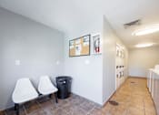 Thumbnail 25 of 142 - Two white chairs are placed in a room with a trash can and a bulletin board.