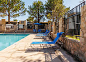 Thumbnail 27 of 142 - A pool with blue chairs and a stone wall.