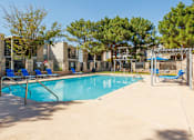 Thumbnail 30 of 142 - A swimming pool surrounded by trees and a building in the background.