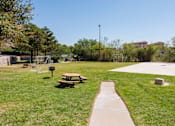 Thumbnail 38 of 142 - A park with a picnic table and a concrete walkway.