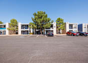 Thumbnail 50 of 142 - A parking lot with cars and apartment buildings in the background.