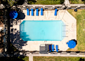 Thumbnail 67 of 142 - An aerial view of a swimming pool surrounded by blue lounge chairs and umbrellas.