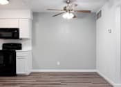 Thumbnail 125 of 142 - A kitchen with a black microwave and oven, white cabinets, and a ceiling fan.