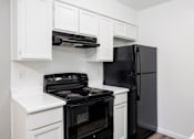 Thumbnail 134 of 142 - A black refrigerator sits next to a black stove in a kitchen.