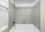 Thumbnail 138 of 142 - A white bathroom with a white tub and toilet.
