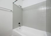 Thumbnail 91 of 142 - A white bathtub in a bathroom with grey tiled walls.